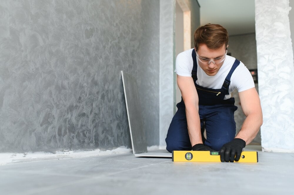 A floor fitter laying floor tiles