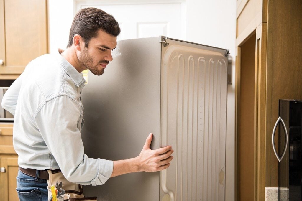 A repair man moving a fridge
